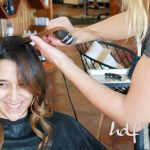 A client smiles while having her hair flat-ironed
