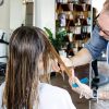 Male hair dresser cutting long hair of client