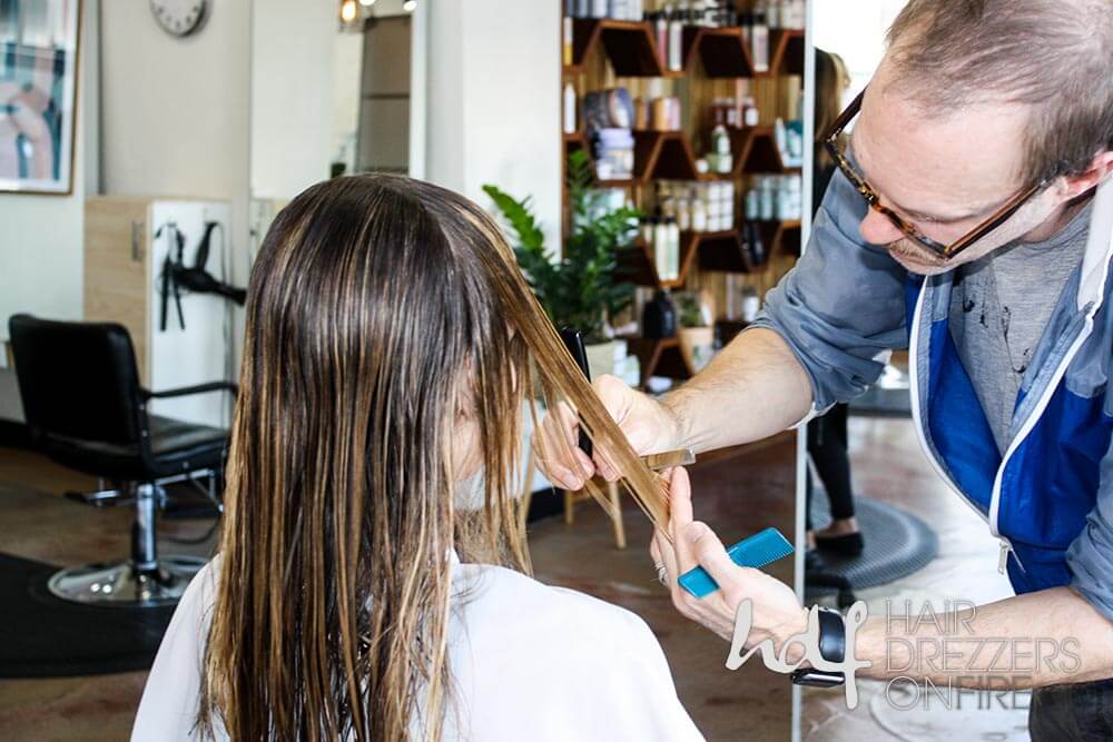 Male hair dresser cutting long hair of client