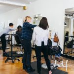 Two hair stylists work with their backs to the camera